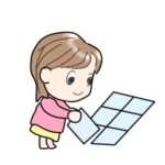 複数のクリアケースを並べて、ジグソーパズル用の下敷きを自作している女性。真剣な表情で作業中。