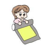 下敷きごとジグソーパズルをやさしく丸めている女性。作業途中のパズルを安全に保管する工夫が伝わる。